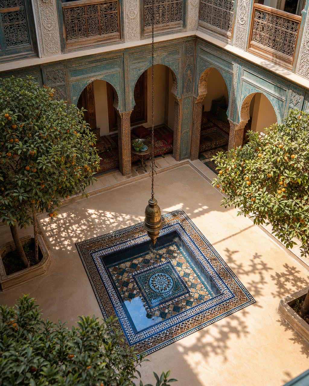 阳光下的 riad 庭院，zellige 瓷砖喷泉、四棵橙树、褪色青绿雪松拱与二楼木格栅光影。